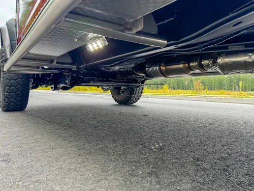 Undercarriage side view showing frame rail, side light, and suspension area.